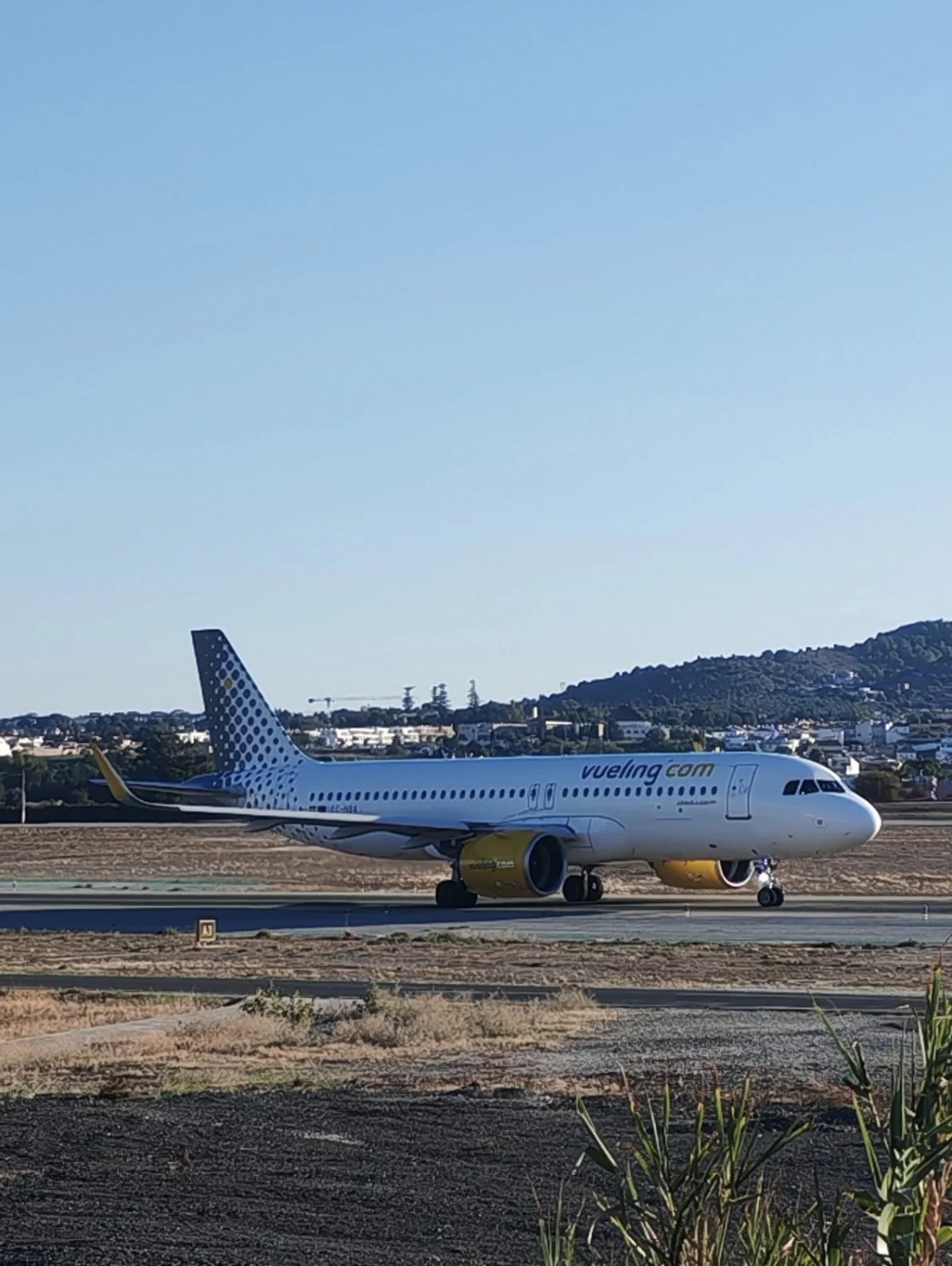 Avión de Vueling rodando por la pista del aeropuerto de Málaga visto desde el mirador de aviones